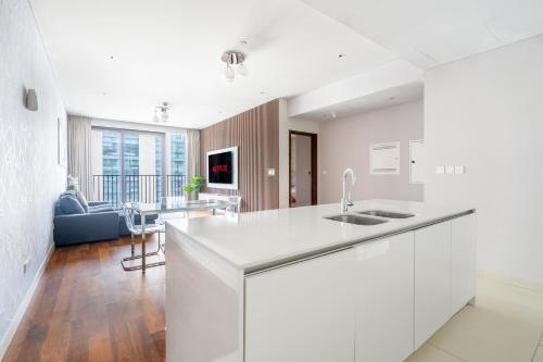 a white kitchen with a sink and a living room at City walk apartment Specter in Dubai