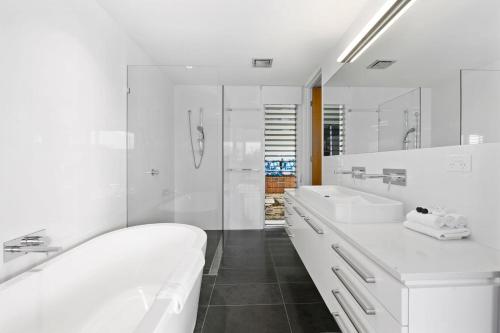 a white bathroom with two sinks and a shower at Sea Bliss in Kingscliff