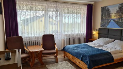 a bedroom with a bed and a chair and a window at Pokoje Gościnne Ster in Władysławowo