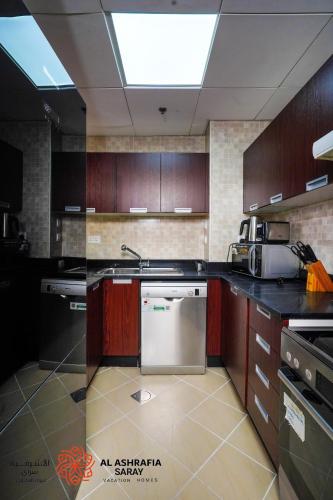a kitchen with wooden cabinets and a stainless steel dishwasher at Alashrafia Saray - Wonderful 1BR in Sports City in Dubai
