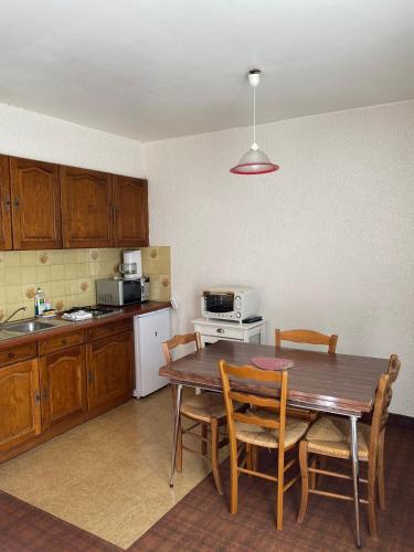uma cozinha com uma mesa e cadeiras de madeira e uma cozinha com um balcão em Motel - location studio 4 personnes em Morbier