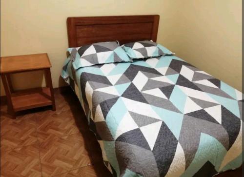 a bed with a black and white comforter and a table at Hospedaje Sumita Wasi in Puno