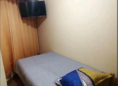 Habitación pequeña con cama y TV. en Hospedaje Sumita Wasi en Puno