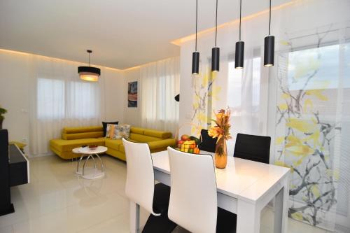 a living room with a white table and a yellow couch at Apartment Bruno - Luxury Penthouse with Jacuzzi in Zadar