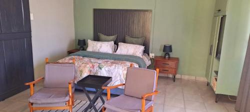 a bedroom with a bed and two chairs at Van Zyls Hoek in Vryburg