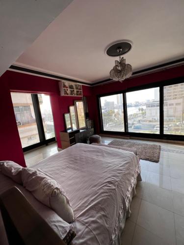 a bedroom with a large bed and large windows at شقة فندقية بانوراما علي النيل in Cairo