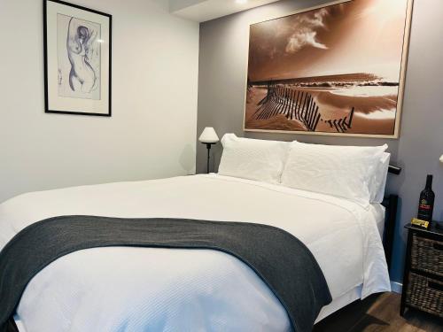 Un dormitorio con una cama blanca con una foto en la pared en River cottage, en Blairgowrie
