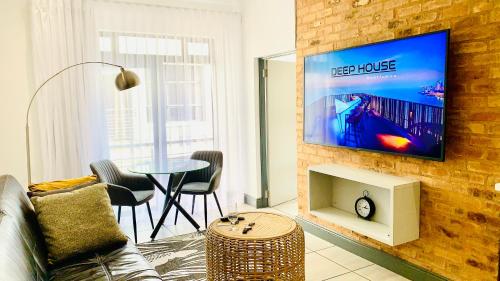 a living room with a television on a brick wall at CALDESMO - Upmarket Apartment in Pretoria