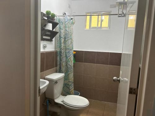 een badkamer met een toilet en een douchegordijn bij A cozy 1 br Scandinavian inspired condo unit near the beach in Davao City