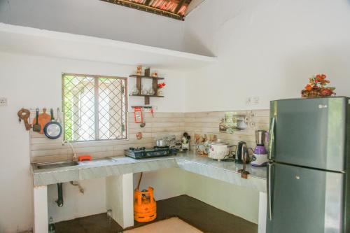a kitchen with a stainless steel refrigerator and a window at Leafy Villa in Mirissa
