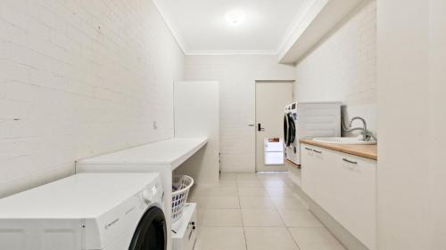 a white laundry room with a sink and a washing machine at Mazza by the Sea - Beachside Family Escape in Lake Tyers