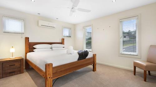 a bedroom with a bed and a chair and windows at Mazza by the Sea in Lake Tyers