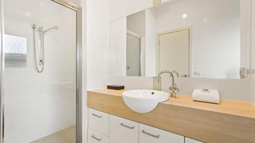a white bathroom with a sink and a shower at Mazza by the Sea in Lake Tyers