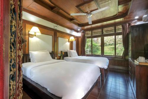 a bedroom with two beds and a window at Artini 2 Cottage Ubud in Ubud