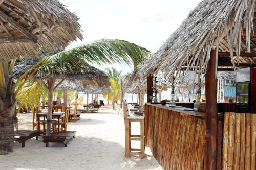 a bar with straw umbrellas and tables on a beach at Mocco Beach Villa in Kendwa