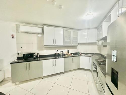 eine große weiße Küche mit weißen Schränken und Geräten in der Unterkunft Stunning 2 Bed - Rooftop Braai Area - Sunset Views in Durban