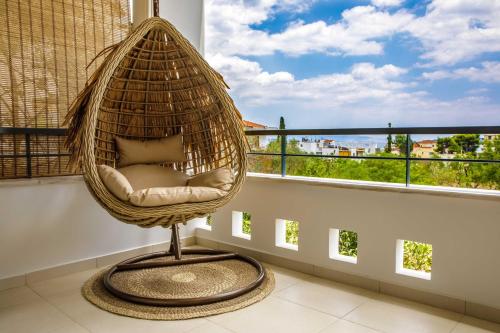 a rattan chair in a room with a window at Savvas Apartment in Tolo