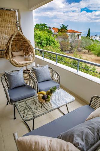 a balcony with wicker chairs and a swing at Savvas Apartment in Tolo