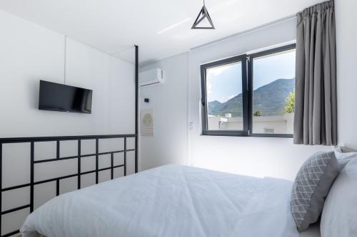 Habitación blanca con cama y ventana en Pagani Blue - Luxury Maisonette A1, en Kalamata