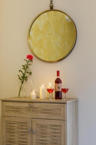 a mirror above a dresser with two glasses of wine at Savvas Apartment in Tolo