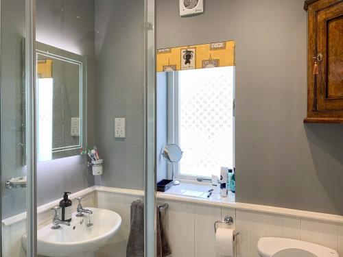 a bathroom with a sink and a toilet and a mirror at Cherry Cottage in Gargrave
