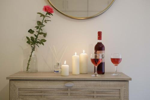 a table with candles and a bottle of wine and two glasses at Savvas Apartment in Tolo