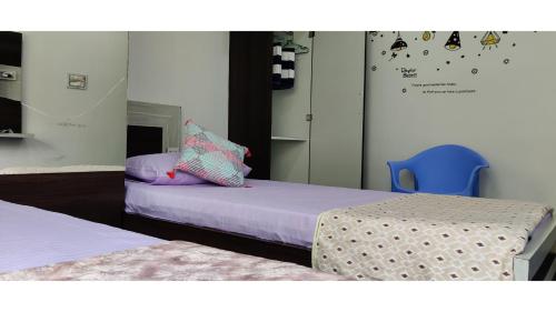 a bedroom with two beds and a blue chair at Anyhour Stay in Gannavaram