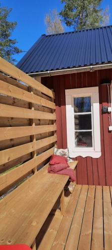 a red building with a bench on a deck at Rosa's stuga in Tasebo