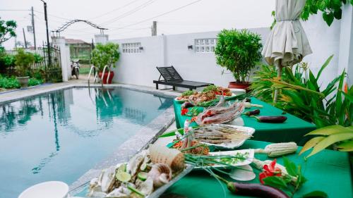 a table with food next to a swimming pool at Tra Que Green Villa Hoi An in Hoi An