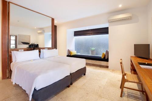 a bedroom with a bed and a desk and a television at Uma Sapna Seminyak in Seminyak