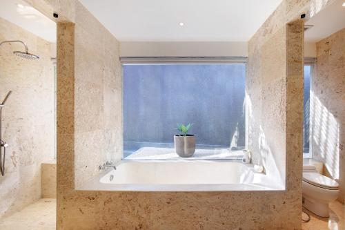 a bath tub in a bathroom with a window at Uma Sapna Seminyak in Seminyak