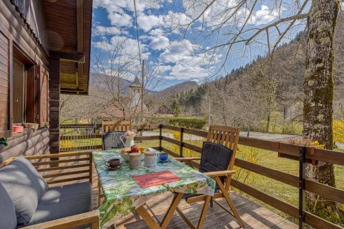 a table and chairs on a deck with a view at Rozi's Riverside Cottage - Happy Rentals in Osilnica