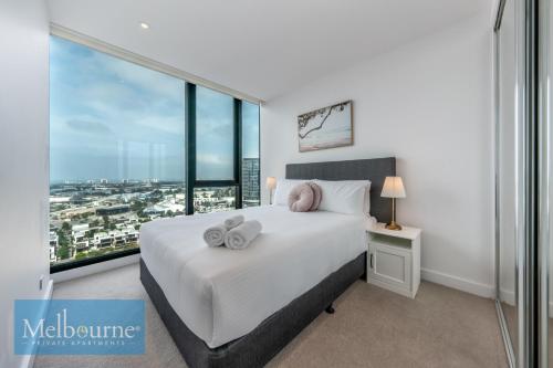 a bedroom with a white bed with a large window at Melbourne Private Apartments - Collins Wharf Waterfront, Docklands in Melbourne