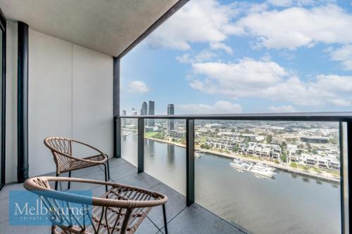 a balcony with two chairs and a view of the water at Melbourne Private Apartments - Collins Wharf Waterfront, Docklands in Melbourne