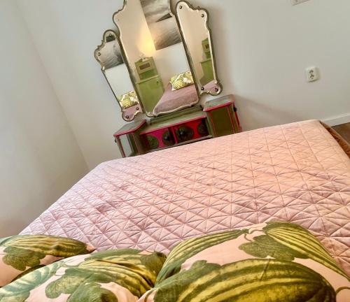 a bedroom with a bed with a pink blanket and two mirrors at Bohemian Eco lodge át lake Balaton in Kisapáti