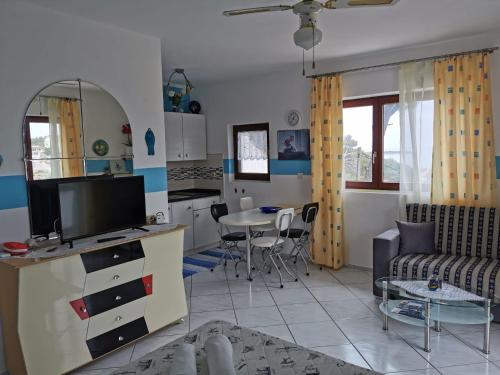 ein Wohnzimmer mit einem TV und einem Tisch mit Stühlen in der Unterkunft Apartmani Nata in Maslinica