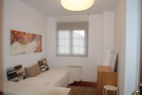 ein weißes Zimmer mit einem Bett und einem Fenster in der Unterkunft Precioso apartamento junto a la ría in Limpias