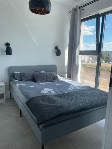 a bed in a bedroom with a large window at Apartament Pendereckiego in Suwałki