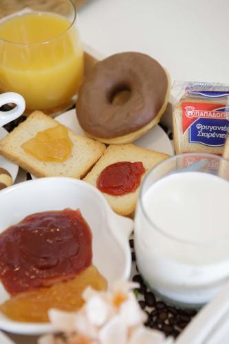 a plate of food with a doughnut and bread and jam at Savvas Apartment in Tolo