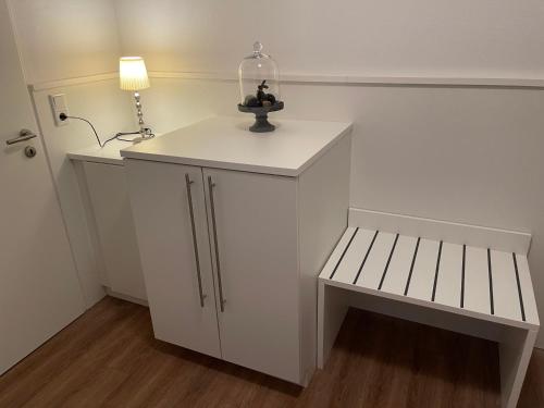 a small white room with a bench and a lamp at Ferien Bungalow Ennens in Rhauderfehn