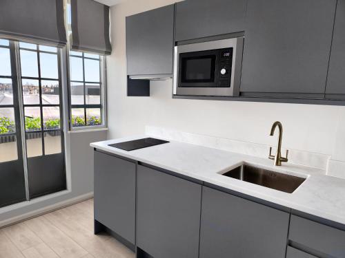 a kitchen with a sink and a microwave at Chelsea Flat 10 mins Harrods, Balcony, Gym, Air Conditioning in London