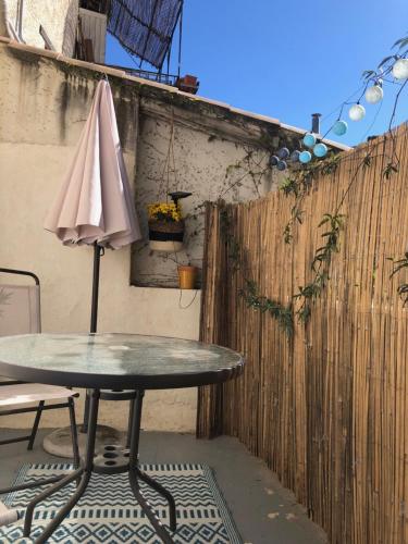 einen Tisch mit einem Regenschirm neben einem Zaun in der Unterkunft Studio Terrasse Clémentine in Avignon