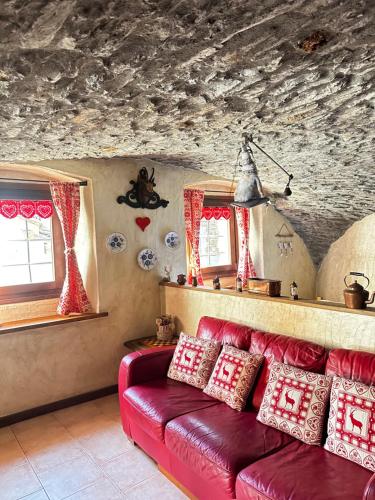 a living room with a red couch and two windows at Casa Netto in Morgex