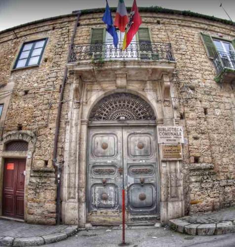 a stone building with a large door with flags on it at B&B AQUILA in Canicattì