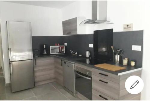 une cuisine avec un réfrigérateur en acier inoxydable et un micro-ondes dans l'établissement Le petit NiCe, à Caromb