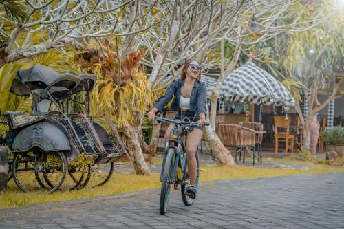 a woman riding a bike down a street at Umadhatu Resort by Amerta in Tabanan
