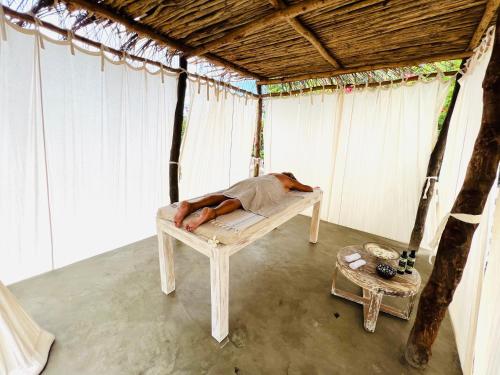 a man laying on a bed in a tent at Beba.Beach.House in Watamu