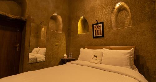 a bedroom with a large bed and a mirror at بيت الصباح نزل وكافيه Bait AlSabah Heritage Inn & Cafe in Birkat al Mawz