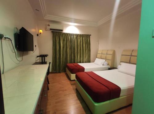 Cette chambre comprend deux lits et une télévision. dans l'établissement OYO 90784 Orkid Inn Kerteh, à Dungun