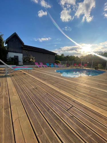 une piscine avec une terrasse en bois et un bâtiment dans l'établissement Gîte 